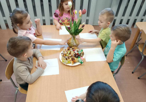 Dzieci siedzą przy stolikach przy słodkim poczęstunku