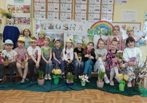 Grupa starszaków pozuje do zdjęcia na tle wiosennej dekoracji.