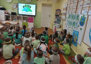 Przedszkolaki oglądają na ekaranie film edukacyjny o Dniu Ziemi.