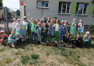 Przedszkolaki prezentują rośliny wsadzone w doniczki.