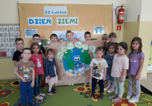 Dzieci prezentują plakat wykonany z okazji Dnia Ziemi.