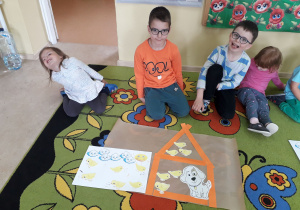 Grupa dzieci prezentuje wykonany domek z pasków dla kurczaczków i przyjaciela Pimpusia Kurki Szóstki.
