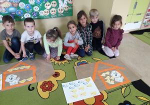 Grupa dzieci prezentuje wykonany domek z pasków dla kurczaczków i przyjaciela Pimpusia Kurki Szóstki.