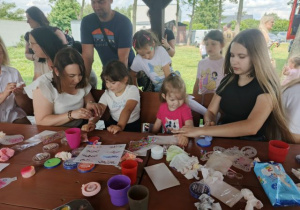 Dzieci z rodzicami w kąciku malowania twarzy i robienia tatuaży.