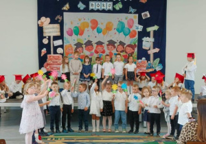 Dzieci z grupy młodszej trzymają kolorowe kwiatki i mówią wierszyk.