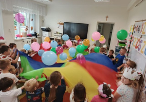 Dzieci podczas zabawy chustą animacyjną i balonami.