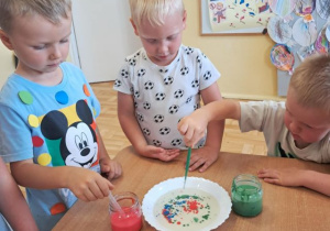 Chłopcy podczas eksperymentu z kolorowymi kropkami na talerzu.