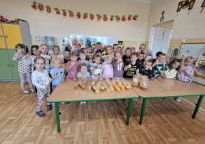 Przedszkolaki pozują do grupowego zdjęcia i prezentują własnoręcznie zrobione soki.
