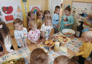 Przedszkolaki obserwują proces wyciskania soku z owoców.