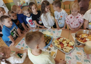 Przedszkolaki obserwują proces wyciskania soku z owoców.