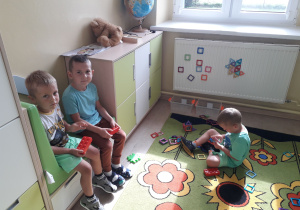 Dwoje chłopców odpoczywa w kąciku relaksacyjnym. Chłopiec na dywanie bawi się magnetycznymi klockami.