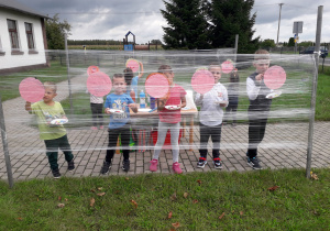 Grupa dzieci maluje swoje portrety w plenerowej strefie kreatywności.