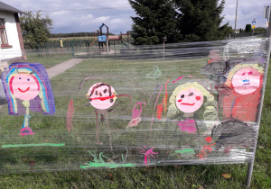 Namalowane portrety dzieci w plenerowej strefie kreatywności.