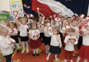 Przedszkolaki trzymają biało-czerwone serca i śpiewają pieśni patriotyczne.
