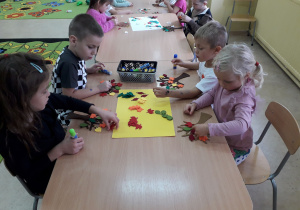 Dzieci przy stolikach wykonują jesienne drzewo.