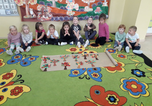 Przedszkolaki prezentują na dywanie wykonane jesienne drzewa.