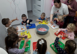 Sala zabaw. Dzieci przy stoliku wykonują gniotka.