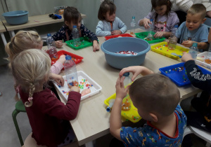 Sala zabaw. Dzieci przy stoliku wykonują gniotka.