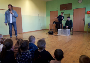 Dzieci podczas audycji muzycznej słuchają prowadzącego audycję.