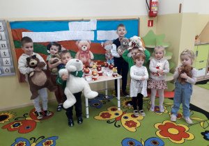 Dzieci ze swoimi pluszowymi misiami pozują na tle dekoracji Święto Pluszowego Misia.