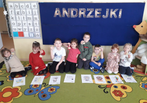 Dzieci na dywanie prezentują swoje znaki zodiaku, trzymając w ręku ciasteczko z wróżbą.
