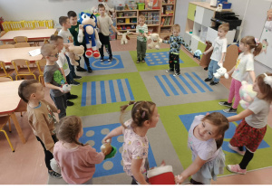 Dzieci tańczą ze swoimi misiami w kole.