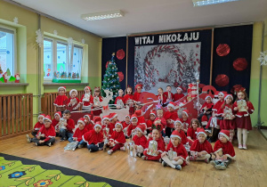 Dzieci pozują do wspólnego zdjęcia z Mikołajem. W tle dekoracja.