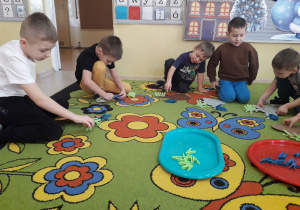 Zabawa matematyczna "Dodawanie z reniferem." Chłopcy przypinają na sylwecie renifera spinacze zgodnie z działaniem dodawania.