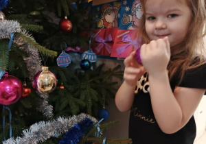 Dziewczynka wiesza ozdobę na choince.