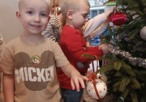 Chłopiec wiesza ozdobę na choince.