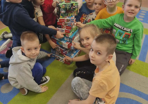 Dzieci z grupy starszej w kręgu pokazują puzzle.