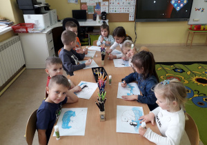 Przedszkolaki przy stoliku wykonują pracę plastyczną "Niedźwiedź polarny."