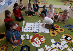 Dzieci na dywanie podczas zabawy matematycznej "Zwierzęta Lodowej Krainy", przeliczają i układają sylwety zwierząt zgodnie z podaną liczbą.