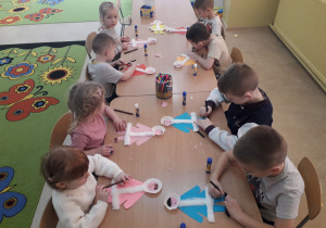 Dzieci przy stolikach wykonują sylwetę Inuity.