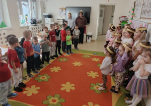 Chłopcy stoją naprzeciwko dziewczynek i składają życzenia z okazji Dnia Kobiet.