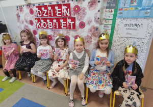 Dziewczyny siedzą na tle dekoracji z prezentami