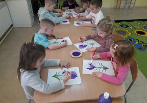 Dzieci podczas malowania farbami sylwet krokusów.