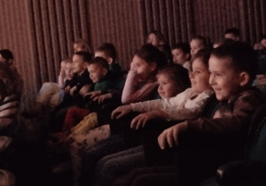 Dzieci siedzą na widowni teatru.