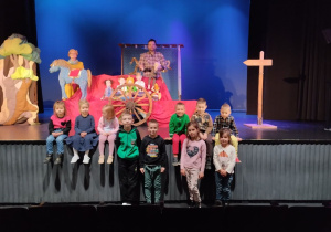 Dzieci pozują do zdjęcia na tle scenografii teatralnej.