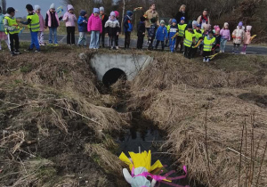 Dzieci stoją w oddali. Przed nimi Marznna wrzucona do wody.
