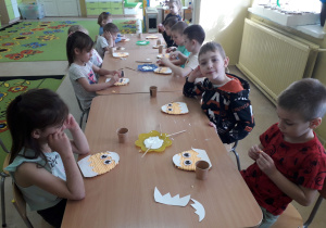 Dzieci przy stolikach podczas tworzenia wielkanocnego kurczaczka.