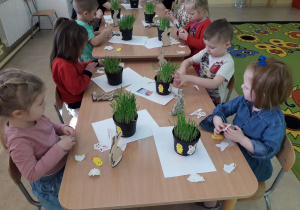 Dzieci przy stolikach komponują stroik wielkanocny.