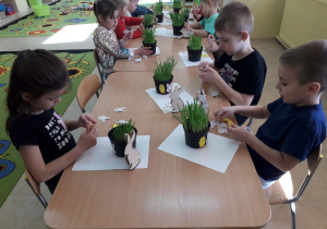 Dzieci przy stolikach komponują stroik wielkanocny.