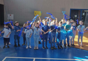 Dzieci pozują do grupowego zdjęcia trzymając wstążki