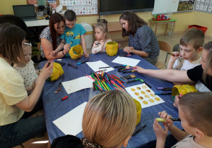 Warsztaty ekologiczne. Mamy i dzieci podczas ozdabiania doniczek z plastikowych butelek.