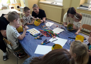 Warsztaty ekologiczne. Mamy i dzieci podczas ozdabiania doniczek z plastikowych butelek.
