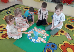 Dzieci podczas zabawy dydaktycznej na dywanie "Uleczymy Ziemię".