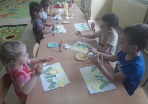 Dzieci podczas pracy plastycznej przy stolikach pt. "Mlecze"