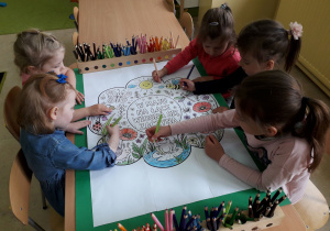 Dziewczynki kolorują ilustrację majowej łąki.