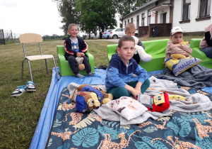 Dzieci w plenerowej strefie czytelniczej podczas akcji "Czytanie na polanie".